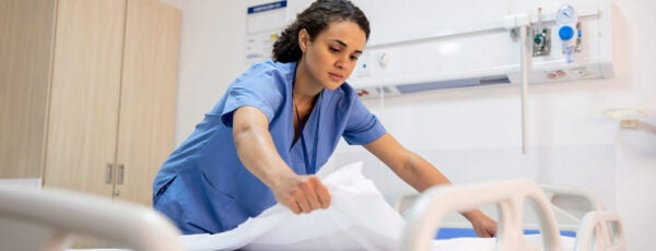 A nurse making a bed in a hospital room to show the racial wealth inequality for workers in health care organizations