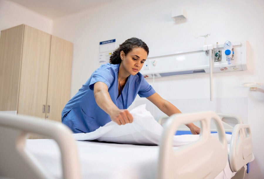 A nurse making a bed in a hospital room to show the racial wealth inequality for workers in health care organizations