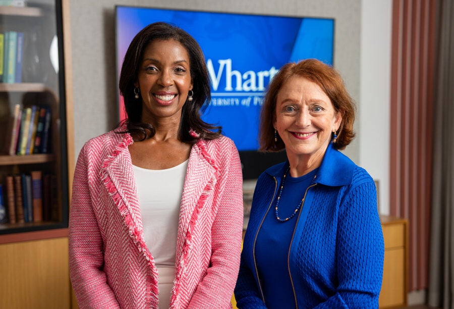 Dean Erika James standing with professor Olivia Mitchell