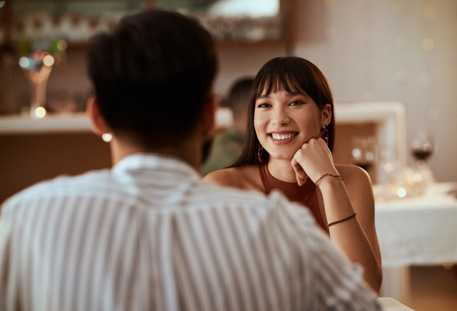 Woman smiling at her date at a fancy restaurant. How did an experiment in speed dating shed light on AI trust?