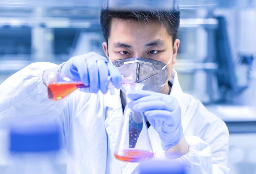 Asian researcher in a lab pouring chemicals into a flask. How are U.S.-China relations hurting science?