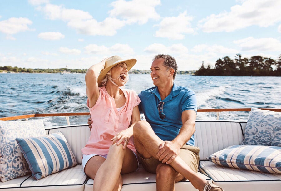 Rich couple laughing on a yacht. Does money buy happiness for millionaires?