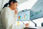 Woman working at a desk with computers screens showing financial information to show the potential of AI-powered financial advice