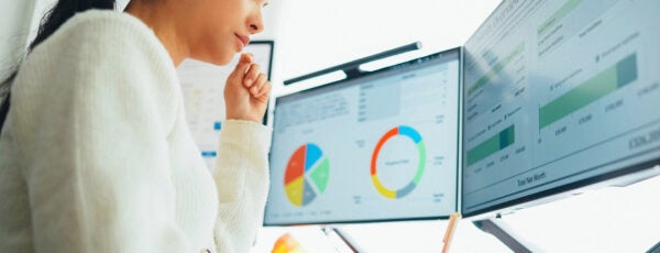 Woman working at a desk with computers screens showing financial information to show the potential of AI-powered financial advice