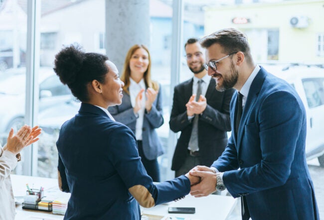 Diverse business team congratulating a colleague for a successful business deal