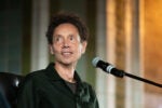 Malcolm Gladwell in a black shirt speaking into a microphone