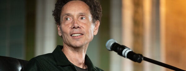 Malcolm Gladwell in a black shirt speaking into a microphone