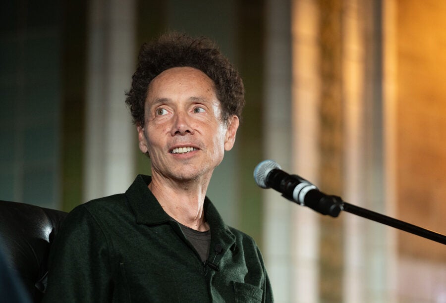 Malcolm Gladwell in a black shirt speaking into a microphone