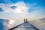 Two technicians in distance discussing between long rows of photovoltaic panels. Why should companies care about their carbon emissions?