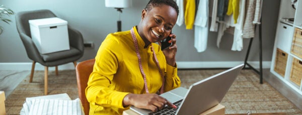 An entrepreneur sitting in their workspace and smiling as they plan their fashion business. Why are some societies more entrepreneurial?