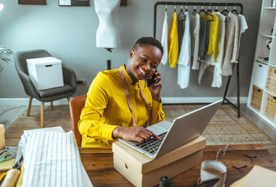 An entrepreneur sitting in their workspace and smiling as they plan their fashion business. Why are some societies more entrepreneurial?