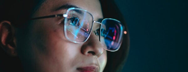 Closeup of a woman's face with a computer screen reflected in her glasses to illustrate the state of AI regulation