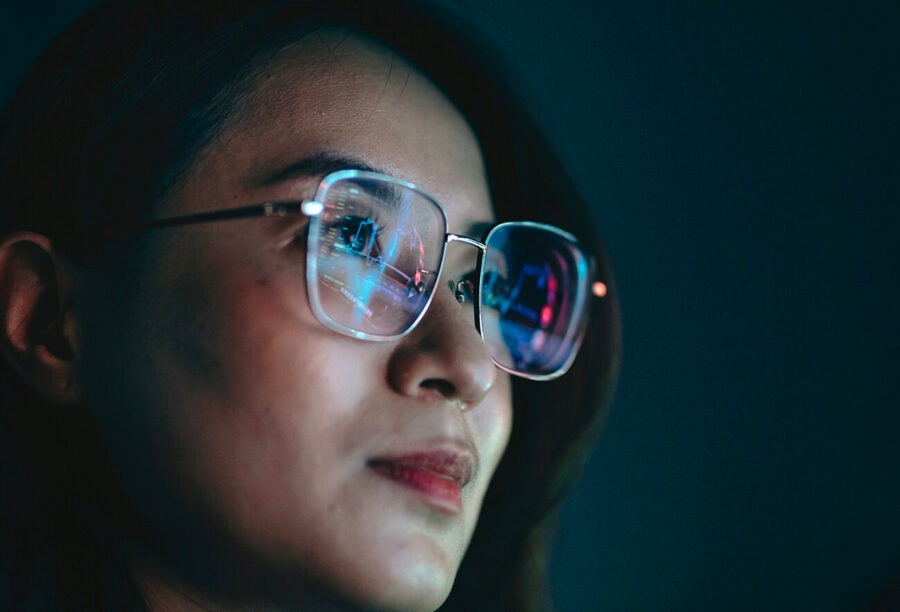 Closeup of a woman's face with a computer screen reflected in her glasses to illustrate the state of AI regulation