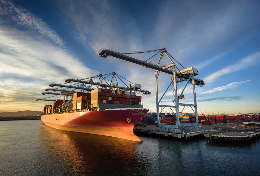 A massive cargo ship loaded with containers docked in the Port of Long Beach.