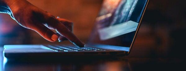 Hand typing on a laptop keyboard.