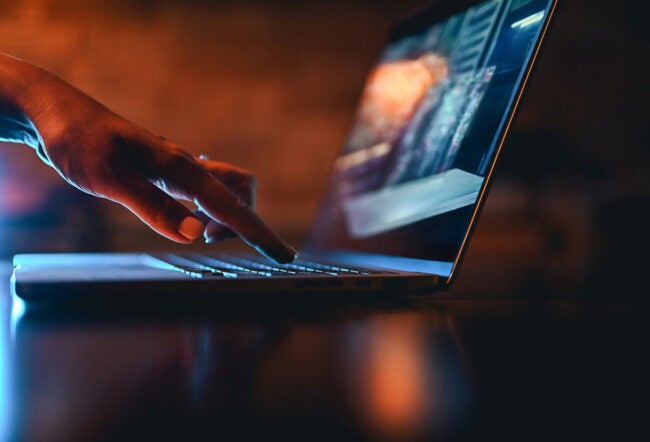 Hand typing on a laptop keyboard.