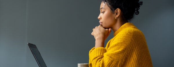 Woman staring contemplatively at her laptop. How can employees find meaning in work?