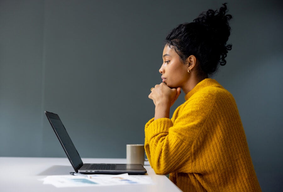 Woman staring contemplatively at her laptop. How can employees find meaning in work?