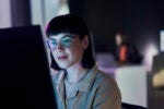 Employee smiling while looking at their computer screen to show human-AI collaboration.