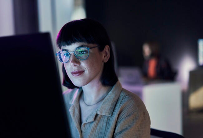 Employee smiling while looking at their computer screen to show human-AI collaboration.