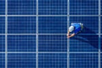 Overhead view of an engineer in protective gear working on solar panels