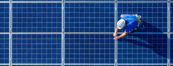 Overhead view of an engineer in protective gear working on solar panels