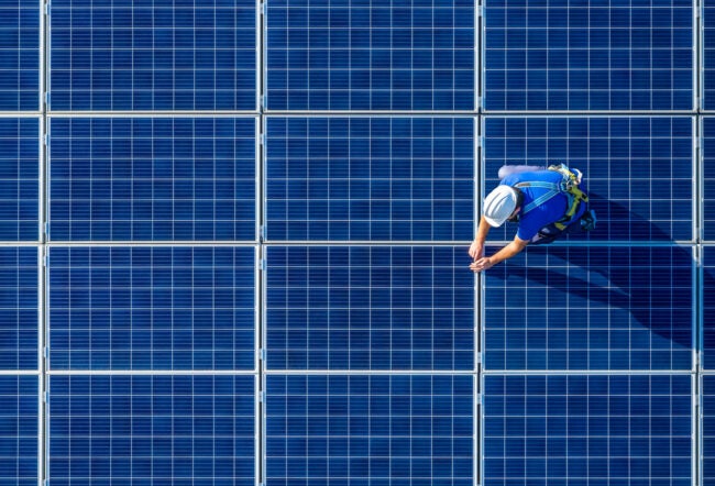 Overhead view of an engineer in protective gear working on solar panels