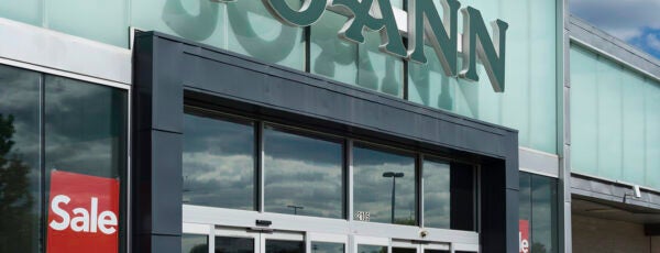 Storefront of a Joann fabrics with the sale signs posted in the window