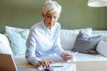 A senior woman sitting in her living room calculating social security taxes