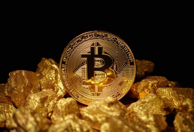 A bitcoin sitting in a pile of gold