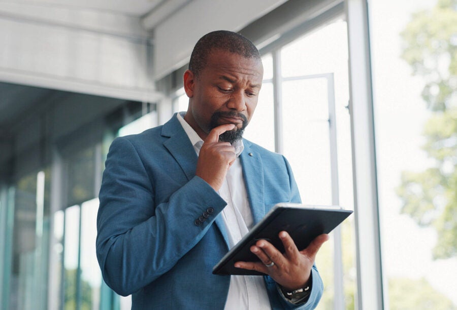 Business man contemplating something on his tablet. How does ambiguity aversion affect investors?