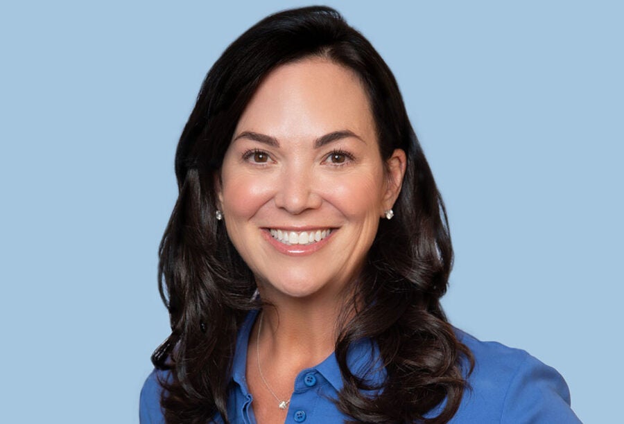 Headshot of Jennifer Tejada smiling in a front of a blue background