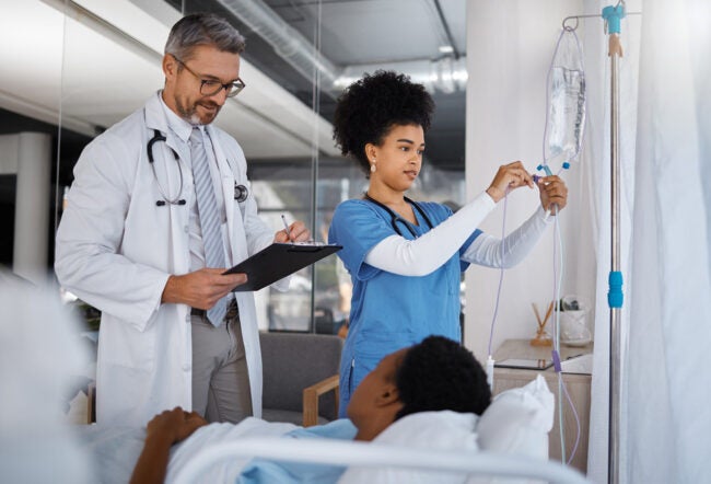A doctor and nurse visiting a patient at their hospital bed.