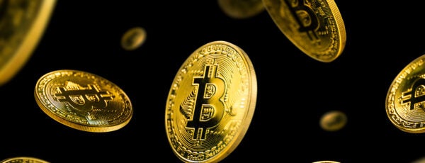 Gold Bitcoin coins falling against a black background.