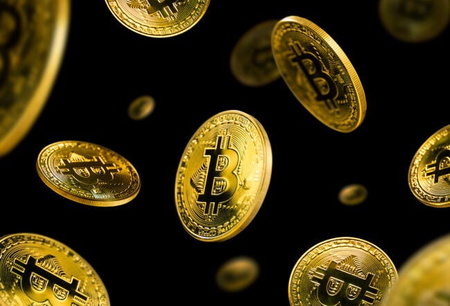 Gold Bitcoin coins falling against a black background.