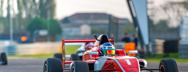 A red formula one racing car leading the race on a motor racing track