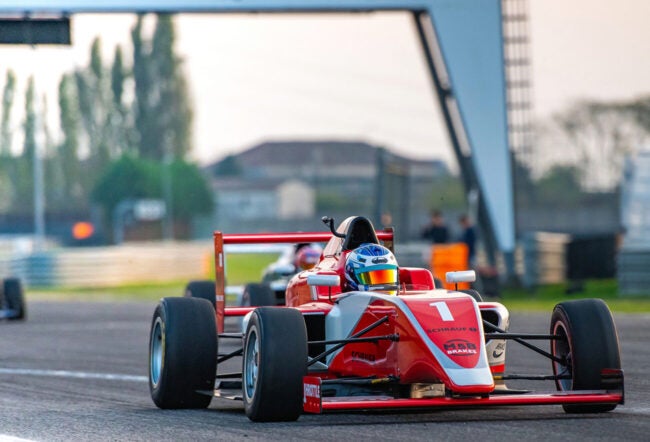 A red formula one racing car leading the race on a motor racing track