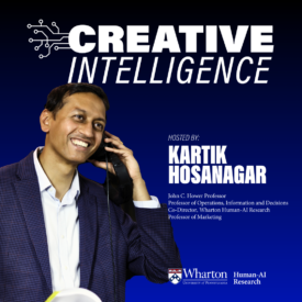Kartik Hosanagar holding a phone to his ear in front of a dark blue background and text that says Creative Intelligence