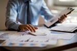 Businessman reviewing finance documents at a desk to show the impact of tariffs on private equity