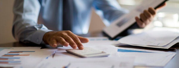 Businessman reviewing finance documents at a desk to show the impact of tariffs on private equity