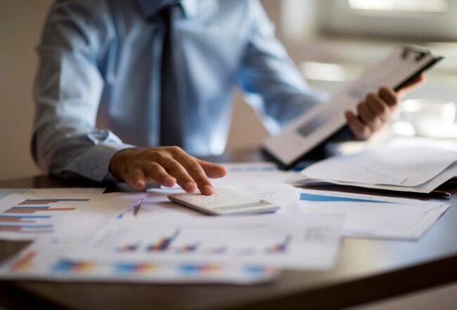 Businessman reviewing finance documents at a desk to show the impact of tariffs on private equity