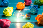 Lightbulb surrounded by colorful crumpled papers