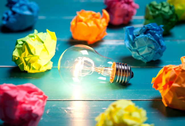 Lightbulb surrounded by colorful crumpled papers