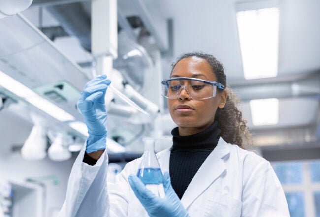 Woman scientist experimenting with chemicals in lab.