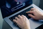 Closeup of hands typing an AI prompt on a laptop