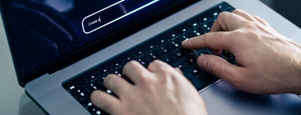 Closeup of hands typing an AI prompt on a laptop