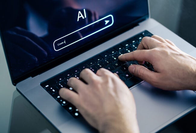 Closeup of hands typing an AI prompt on a laptop
