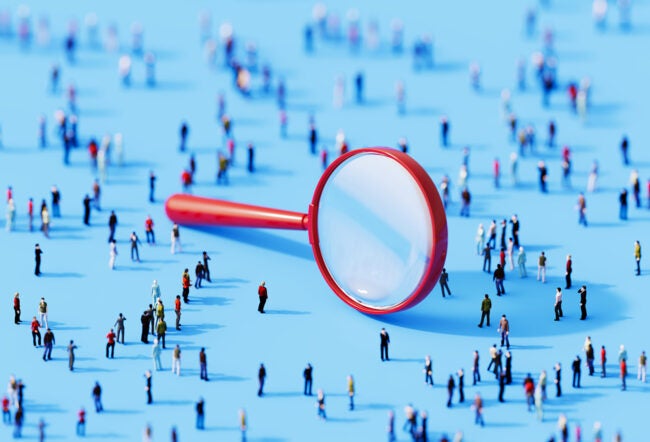 3D illustration of a giant magnifying glass surrounded by a crowd of people to show how firm-driven search impacts startup growth