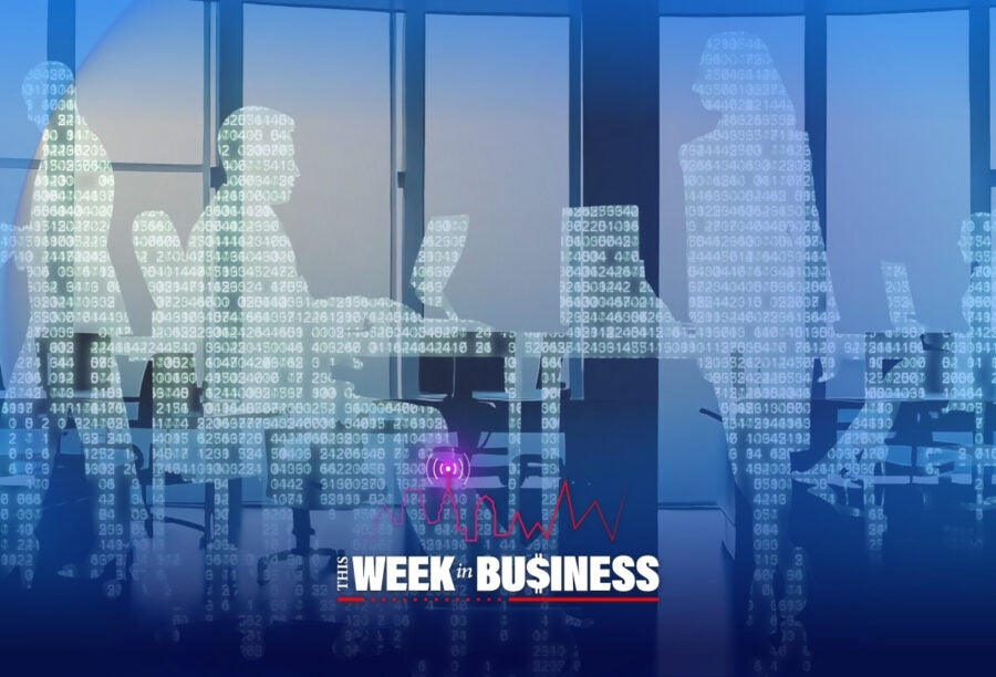 Silhouettes of people in an office with computer code overlay, depicting a digital business environment. The text "The Week in Business" is at the bottom.