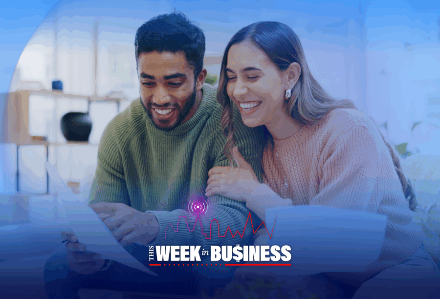 A couple is smiling while looking at a document together in a cozy setting. The image includes the text "This Week in Business" with a city skyline and graph icon overlay.